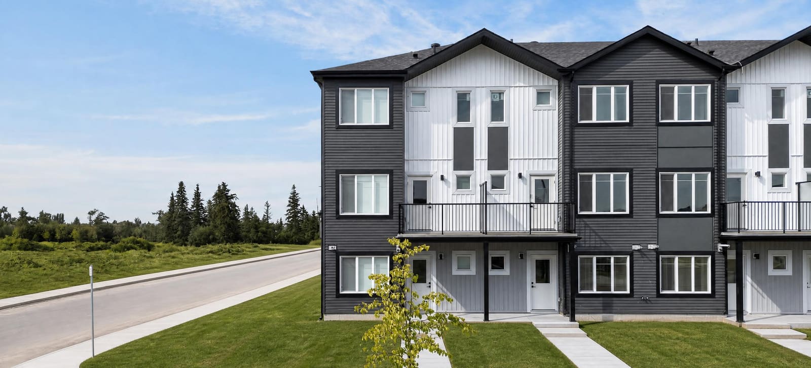 Corner townhome block with balconies, lawns and young street trees at The Villas at Cavanagh Ravine
