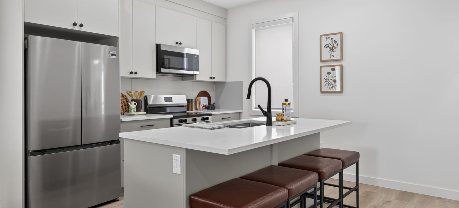 Show home kitchen with island seating, full-height cabinetry and included appliances